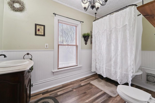bathroom featuring toilet, wainscoting, vanity, crown molding, and wood finished floors