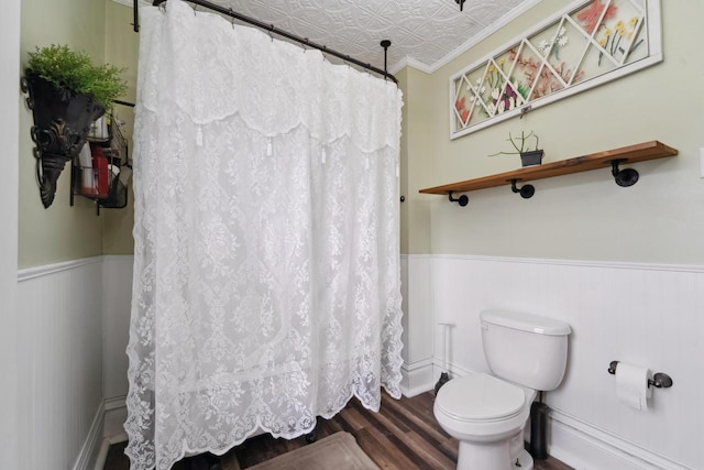 full bathroom with wainscoting, toilet, an ornate ceiling, and wood finished floors