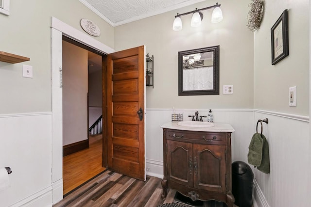 bathroom featuring vanity, ornamental molding, wainscoting, and wood finished floors