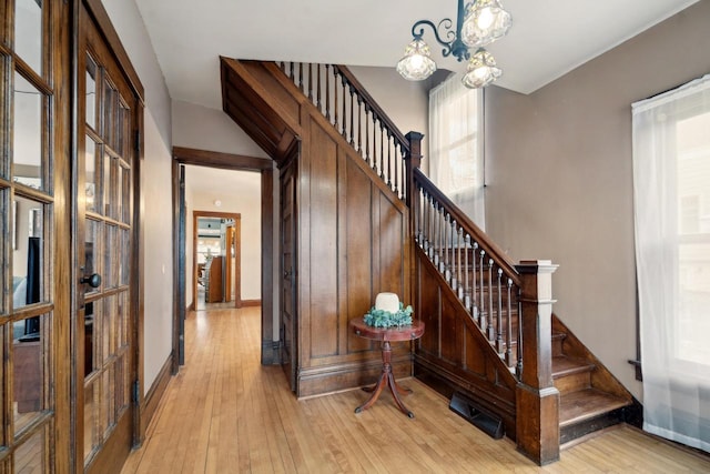 stairway featuring baseboards, a notable chandelier, and hardwood / wood-style floors