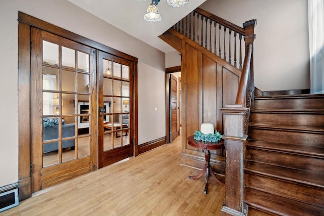 interior space featuring french doors, wood finished floors, and a notable chandelier