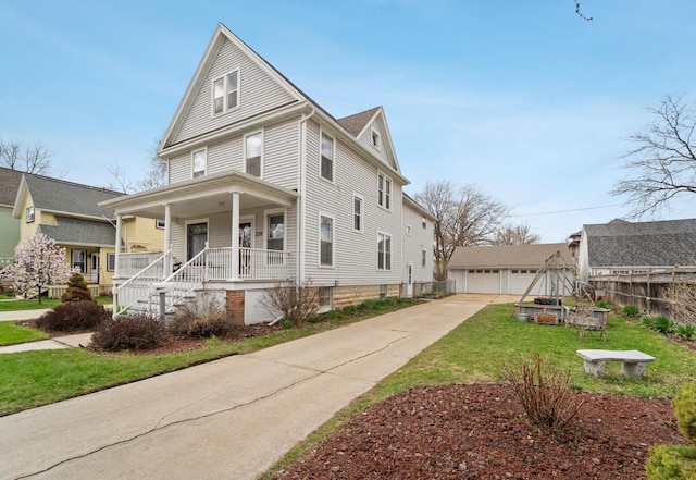 traditional style home featuring a front yard, covered porch, fence, and a detached garage