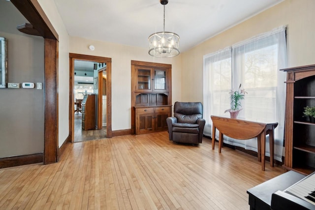 sitting room with light wood-style floors, a chandelier, and baseboards