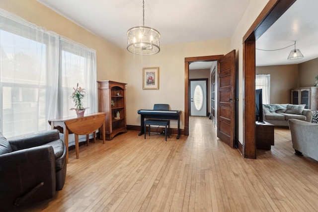 sitting room featuring baseboards, a notable chandelier, and light wood finished floors