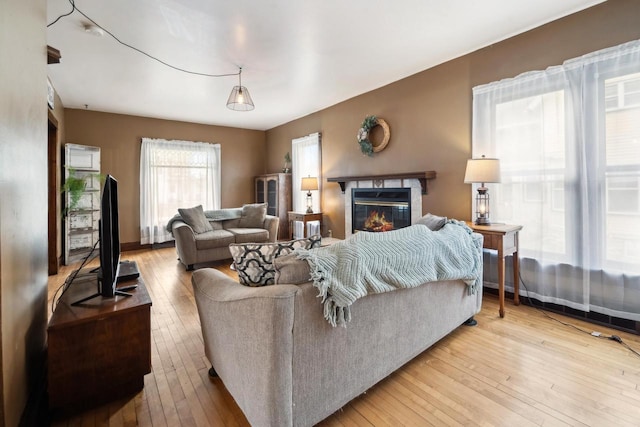 living area featuring wood-type flooring, baseboards, and a glass covered fireplace