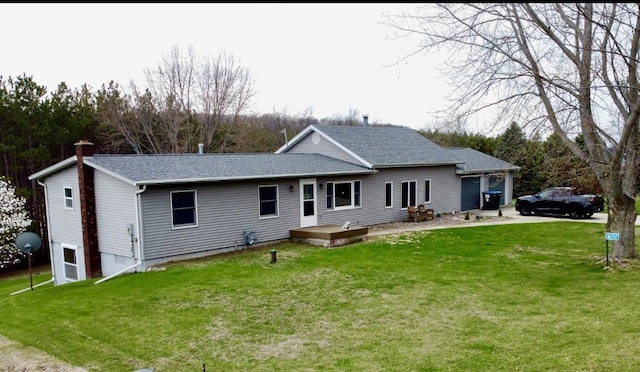 back of house featuring roof with shingles, a chimney, and a lawn
