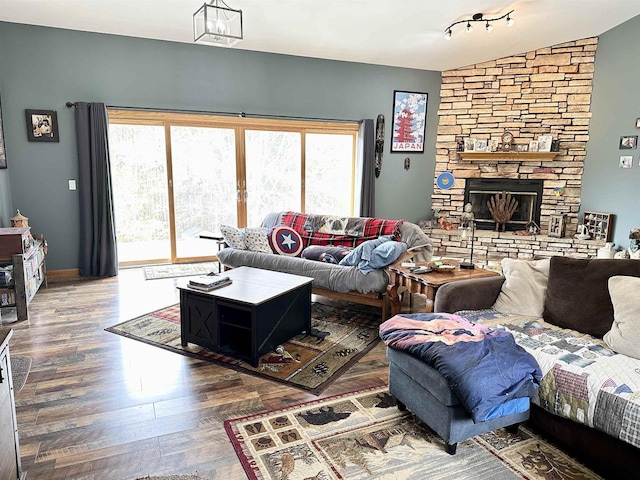 living room featuring baseboards, vaulted ceiling, wood finished floors, and a fireplace