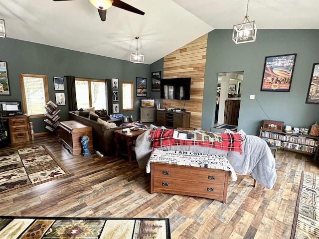 living area featuring wood finished floors, ceiling fan with notable chandelier, and high vaulted ceiling