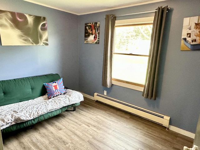 sitting room featuring ornamental molding, baseboards, baseboard heating, and wood finished floors