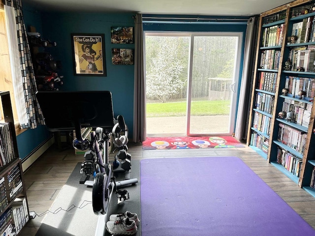 workout room with a baseboard radiator and wood finished floors