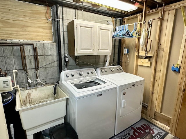laundry room with washing machine and dryer, a sink, and cabinet space