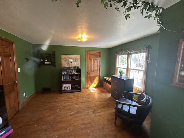 sitting room featuring a textured ceiling, baseboards, and wood finished floors