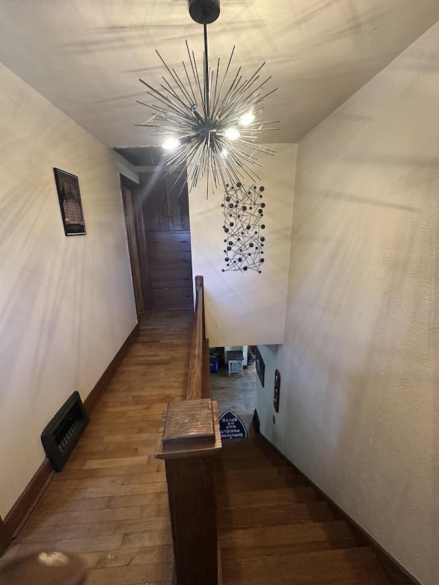 staircase with baseboards, a notable chandelier, and wood finished floors
