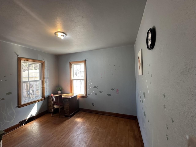 unfurnished office featuring a wealth of natural light, baseboards, and wood finished floors
