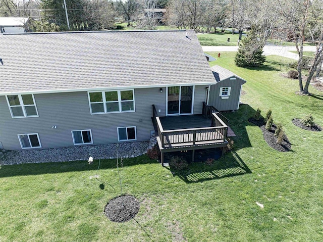 back of property featuring a lawn, roof with shingles, and a wooden deck