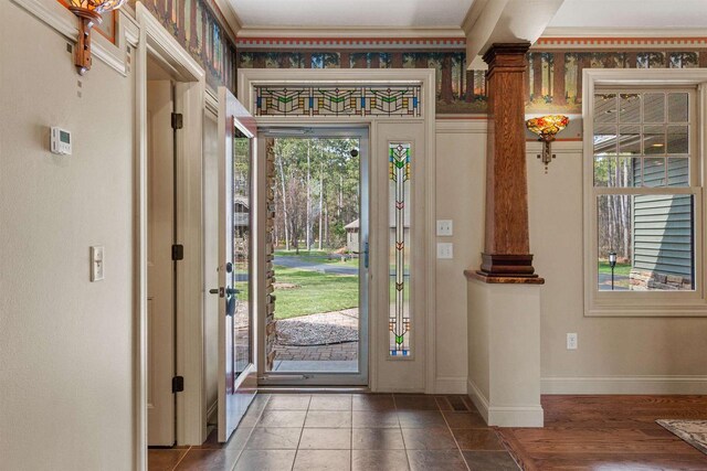 entryway featuring baseboards, crown molding, and decorative columns