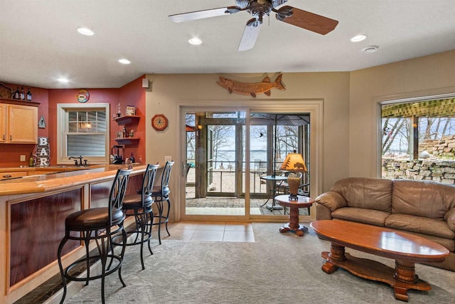 living area featuring indoor bar, light colored carpet, light tile patterned flooring, recessed lighting, and ceiling fan