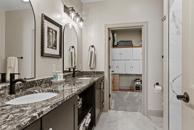 full bath featuring a sink, double vanity, baseboards, and marble finish floor