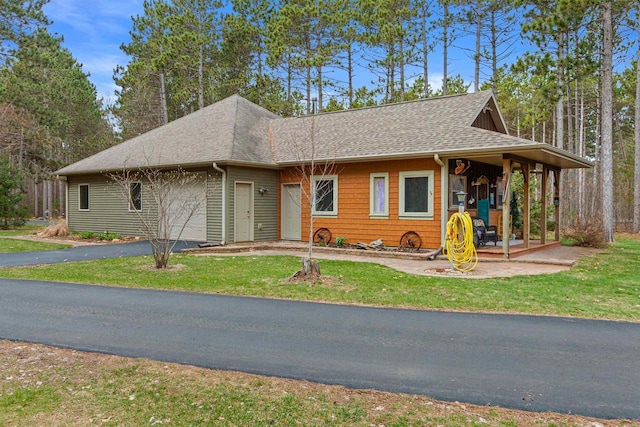 view of front facade with a shingled roof, a front yard, driveway, and a garage