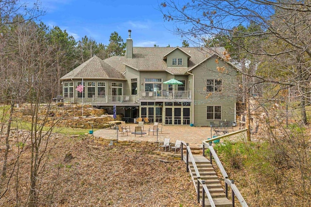 back of house featuring roof with shingles, stairs, a patio, a wooden deck, and a chimney