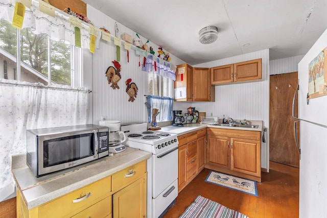 kitchen featuring white appliances, light countertops, wallpapered walls, and a sink