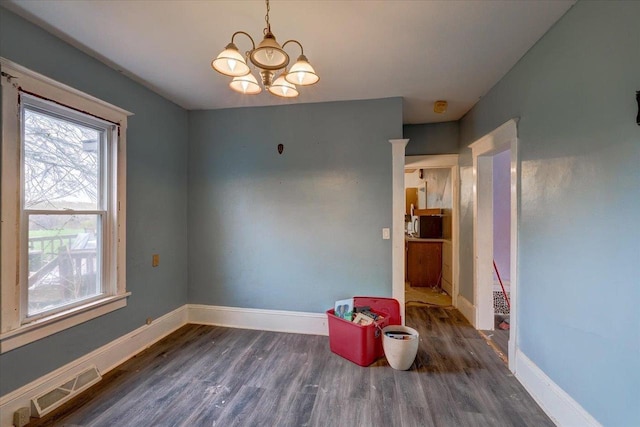 unfurnished room featuring a chandelier, baseboards, visible vents, and wood finished floors