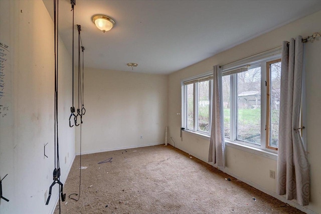 unfurnished room featuring light carpet and baseboards