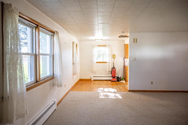 spare room with baseboards, baseboard heating, and light colored carpet