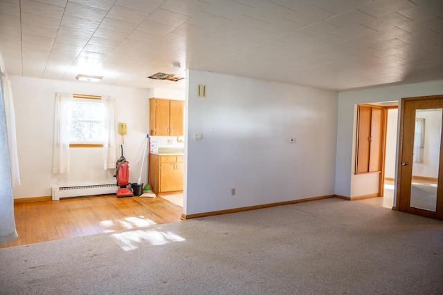 unfurnished living room featuring a baseboard heating unit, baseboards, light colored carpet, and light wood-style floors
