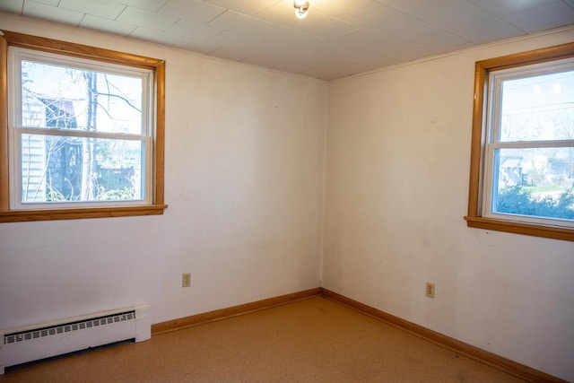 empty room featuring a baseboard radiator, light carpet, and baseboards
