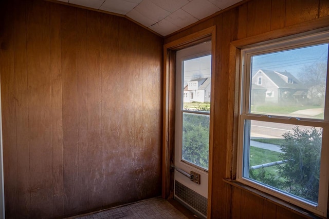 doorway with wood walls and vaulted ceiling