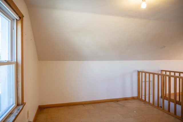 additional living space featuring plenty of natural light, vaulted ceiling, and light floors
