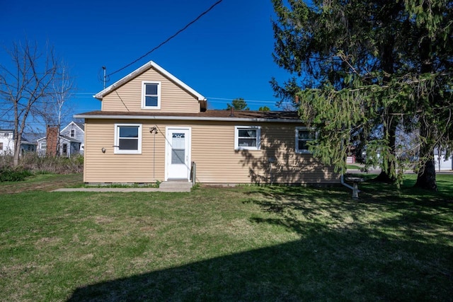 rear view of property featuring a yard and entry steps