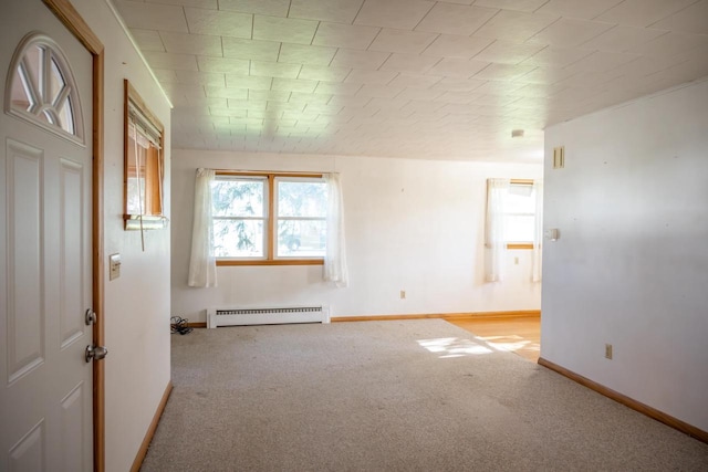 carpeted empty room with a baseboard heating unit and baseboards