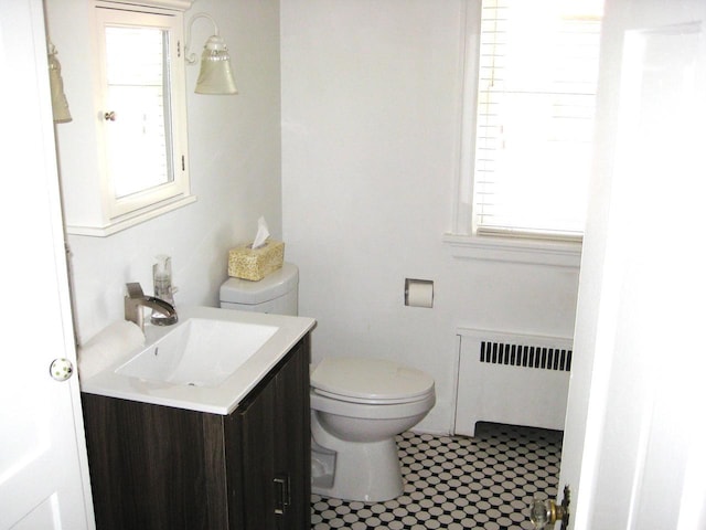 bathroom with toilet, radiator, tile patterned floors, and vanity