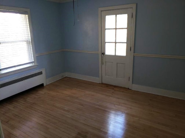 spare room featuring a wealth of natural light, wood finished floors, and baseboards