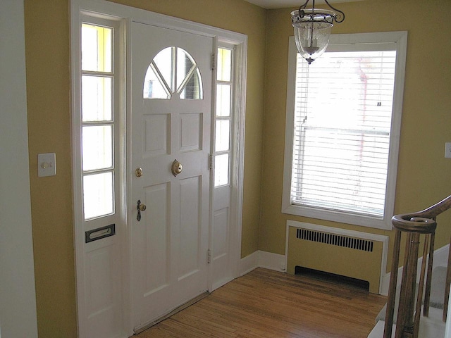 entryway with radiator, a wealth of natural light, wood finished floors, and baseboards