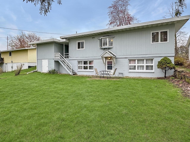 back of property featuring a lawn and stairway