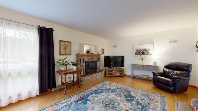 living area featuring wood finished floors, visible vents, and a fireplace