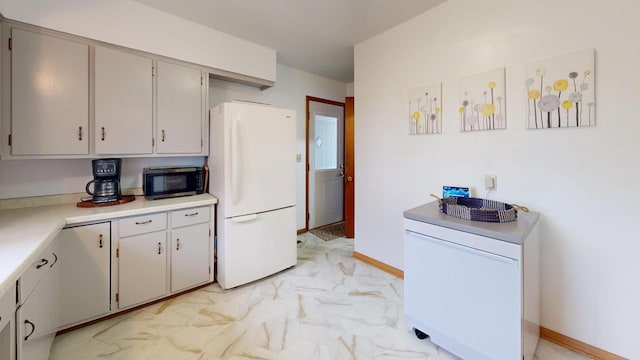 kitchen featuring freestanding refrigerator, baseboards, marble finish floor, stainless steel microwave, and light countertops
