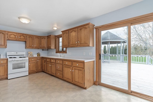 W11330 Rose Eld Rd, Ripon, WI 54971 - kitchen featuring light floors, white range with gas cooktop, light countertops, and brown cabinets