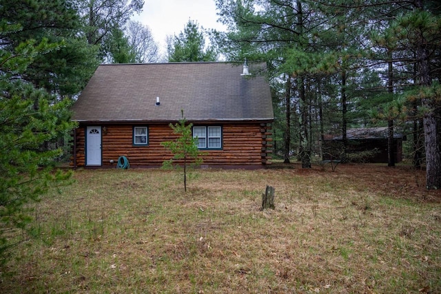 rear view of house featuring log siding, roof with shingles, and a yard
