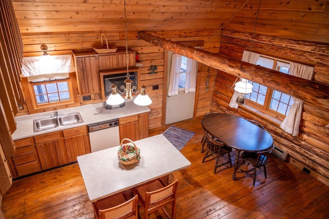 kitchen featuring dishwasher, light wood finished floors, a sink, brown cabinets, and light countertops