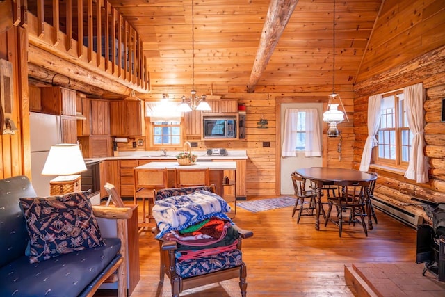living area with baseboard heating, light wood finished floors, plenty of natural light, and vaulted ceiling