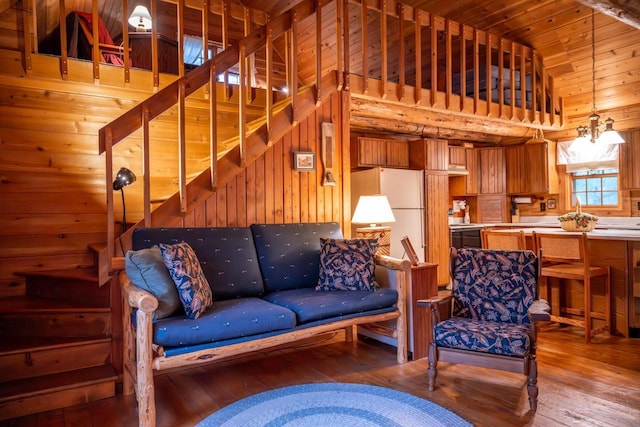 living area featuring hardwood / wood-style flooring, vaulted ceiling, wood walls, and stairway