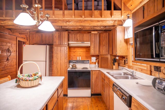 kitchen with under cabinet range hood, brown cabinetry, white appliances, a sink, and light countertops