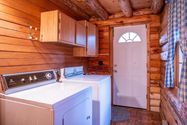 clothes washing area featuring cabinet space, washing machine and clothes dryer, wood ceiling, and rustic walls
