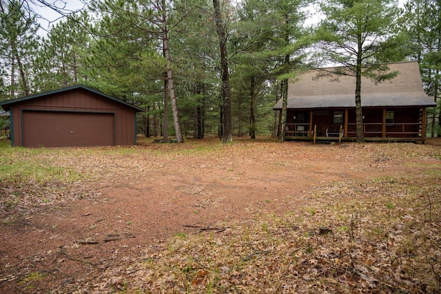 view of yard featuring covered porch, a detached garage, and an outbuilding
