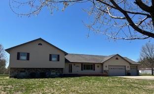 split level home with an attached garage, a front lawn, and driveway