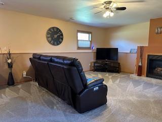 carpeted living room with a fireplace and ceiling fan